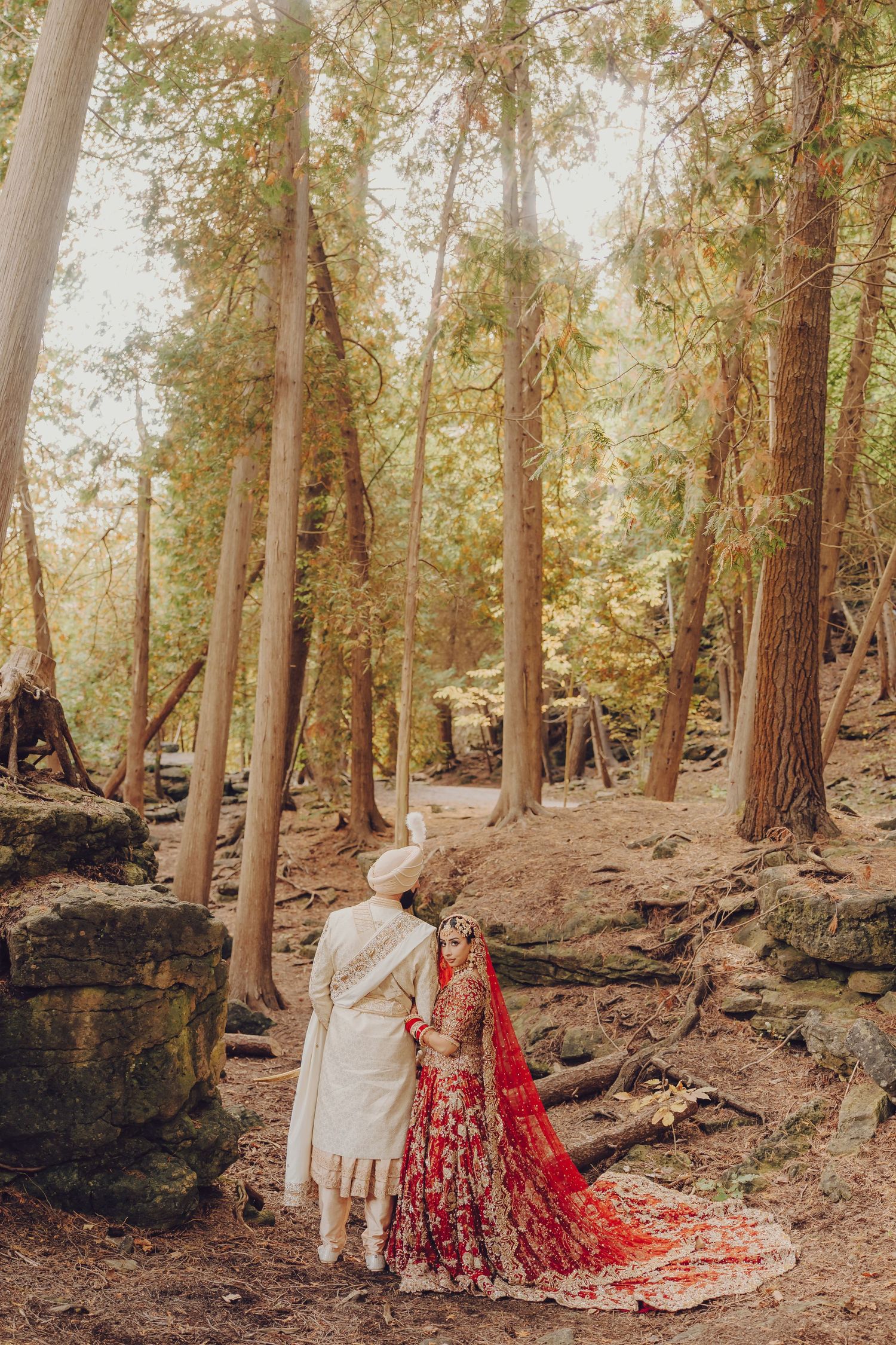 A series of romantic forest photos showing a couple among tall trees with one wearing a flowing red dress.