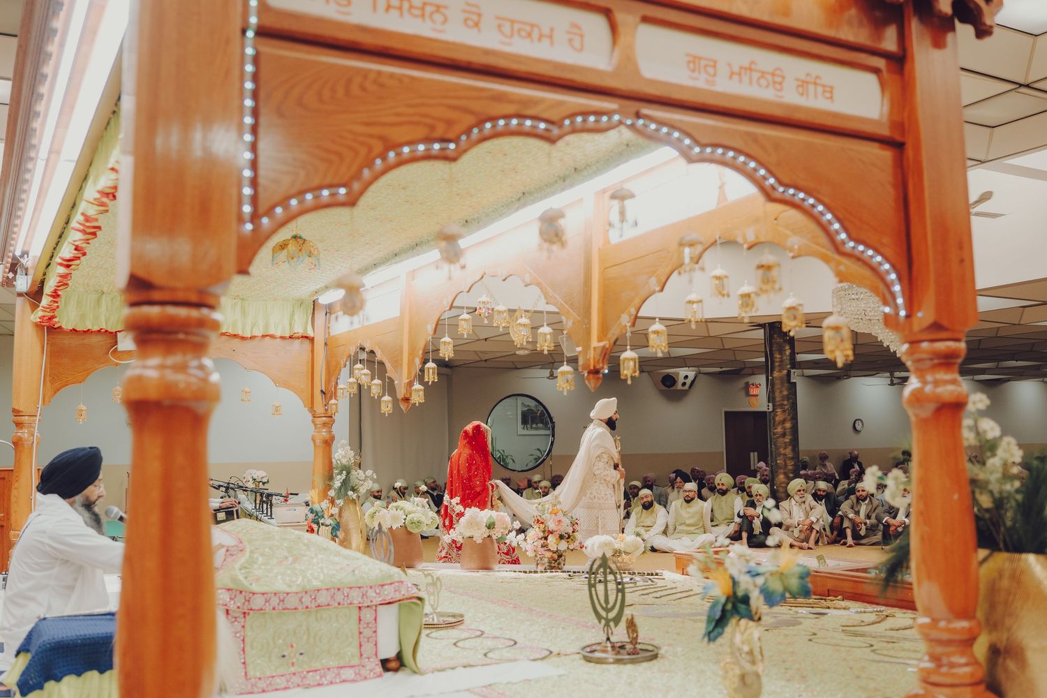 Panoramic view of a decorated wedding venue with orange archways and traditional Indian architecture.