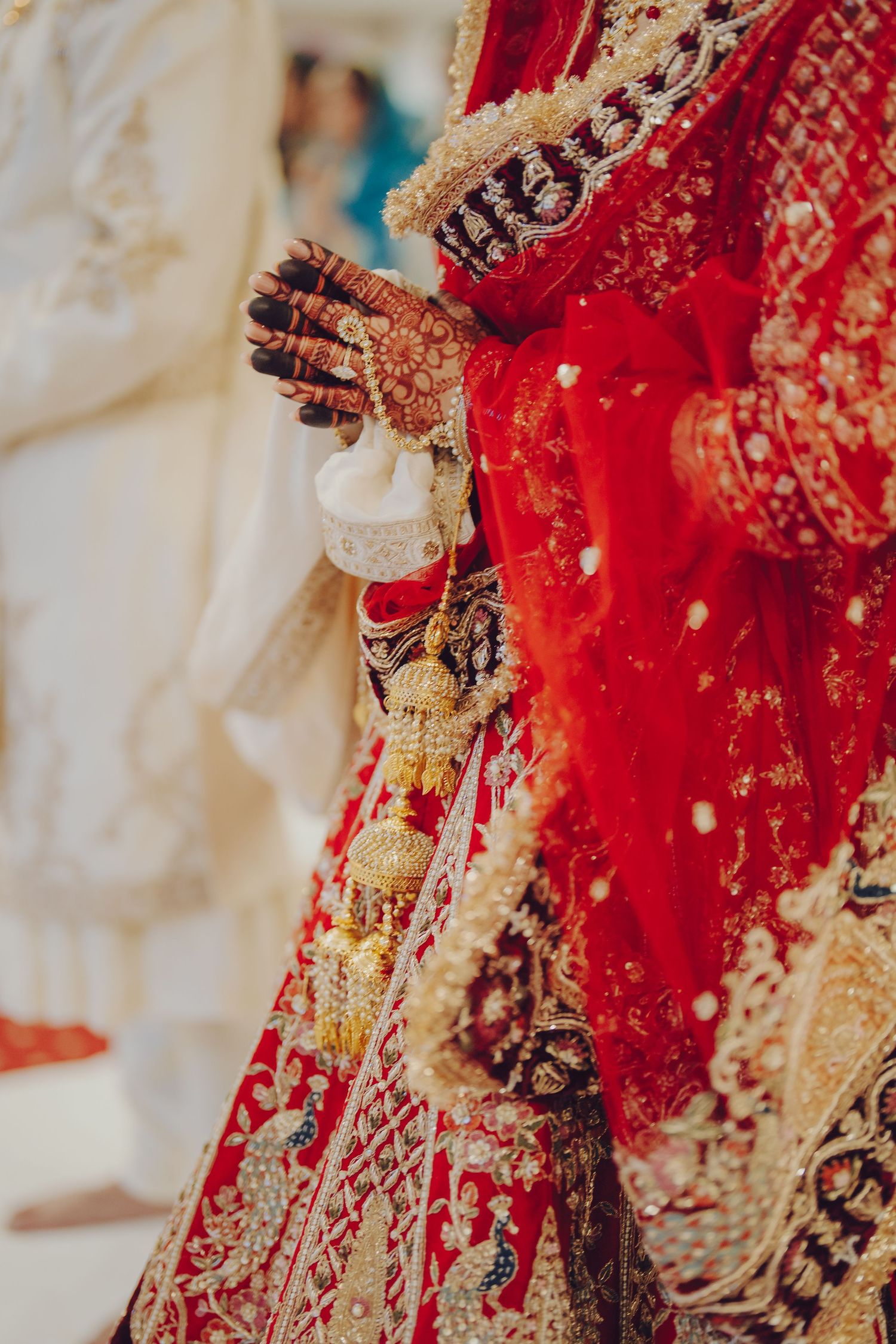Close-up detail of ornate red and gold Indian bridal attire with traditional embroidery and jewelry.