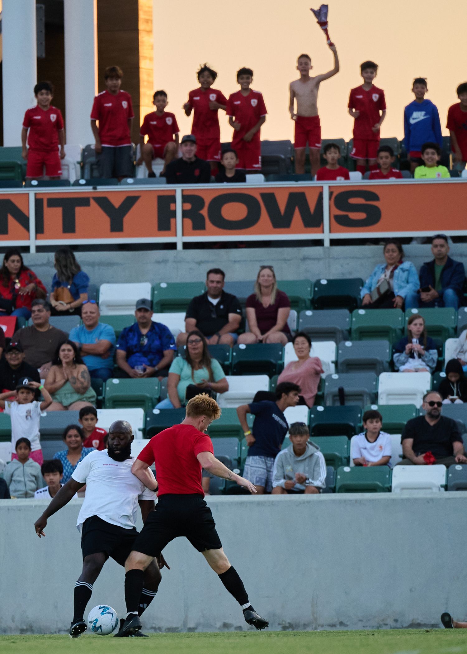 Soccer players diving and stretching to reach for the ball during an intense match on the field.