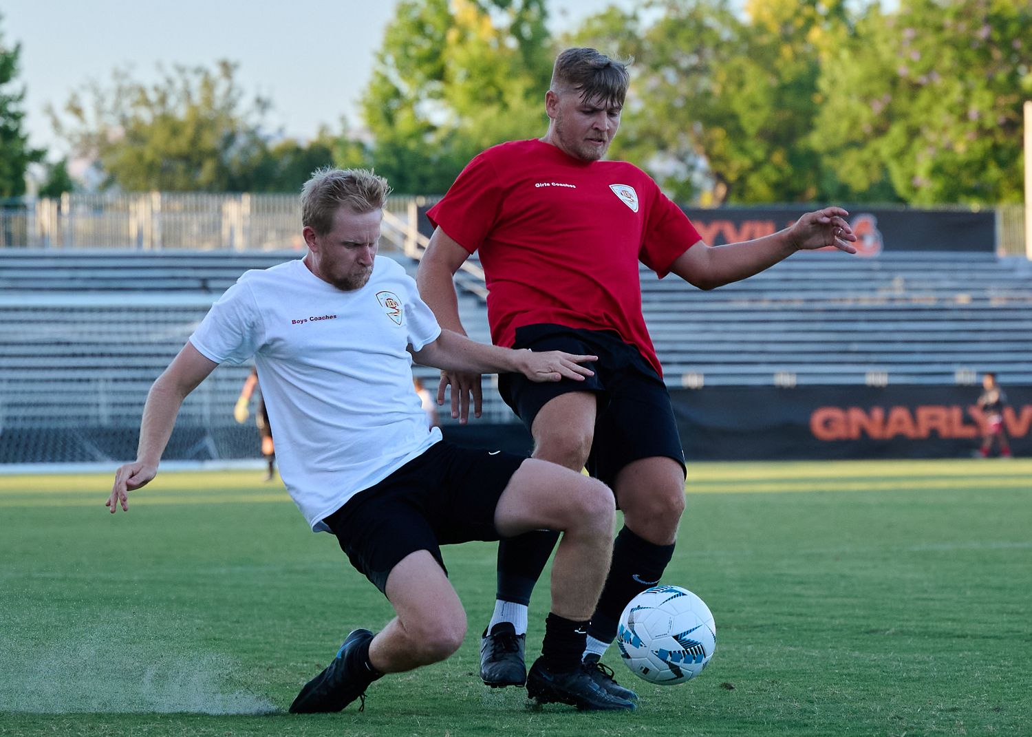 Soccer players compete for possession of the ball during an intense match on a grass field.