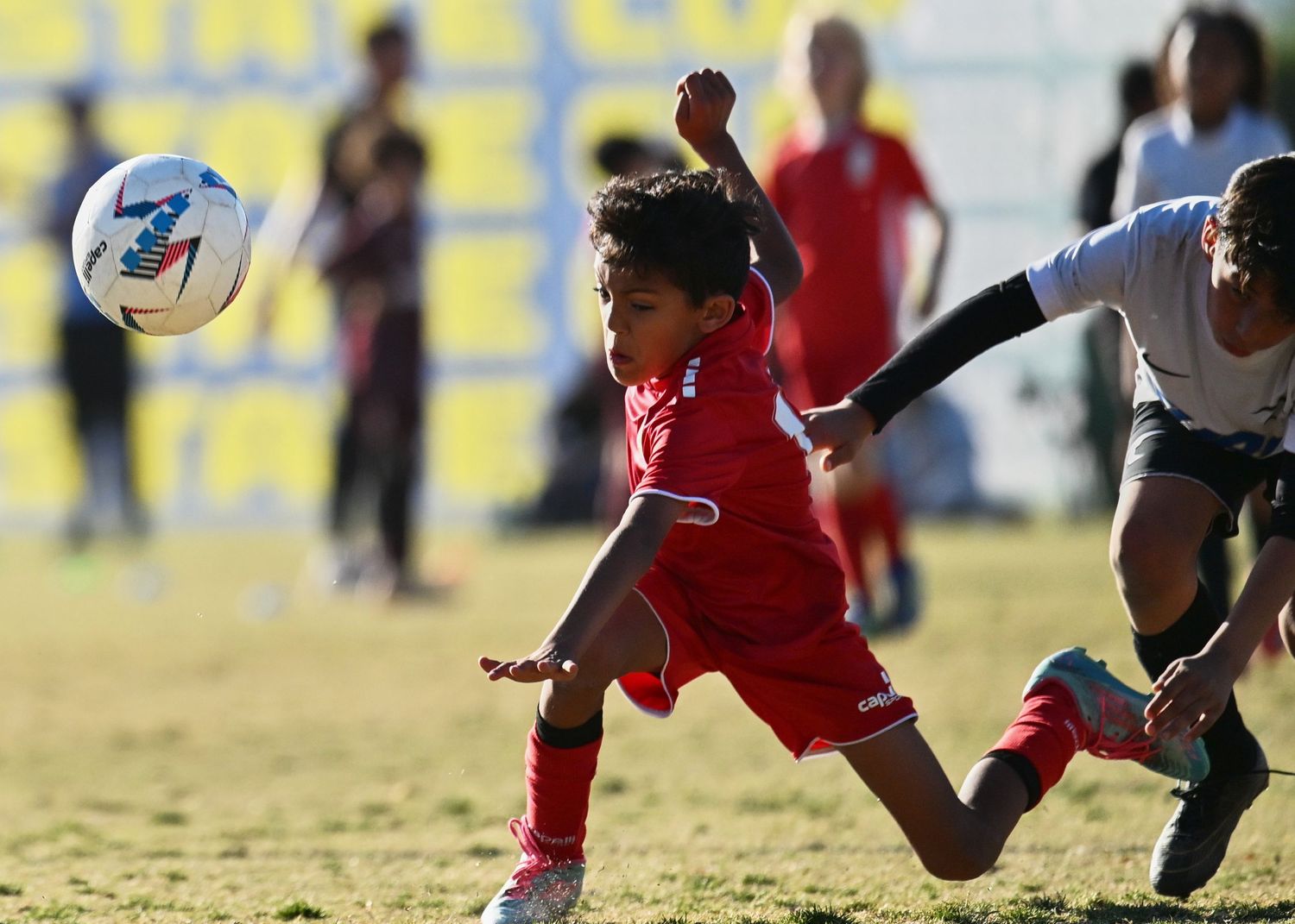 A player in red makes an acrobatic move to control the ball during a soccer match.