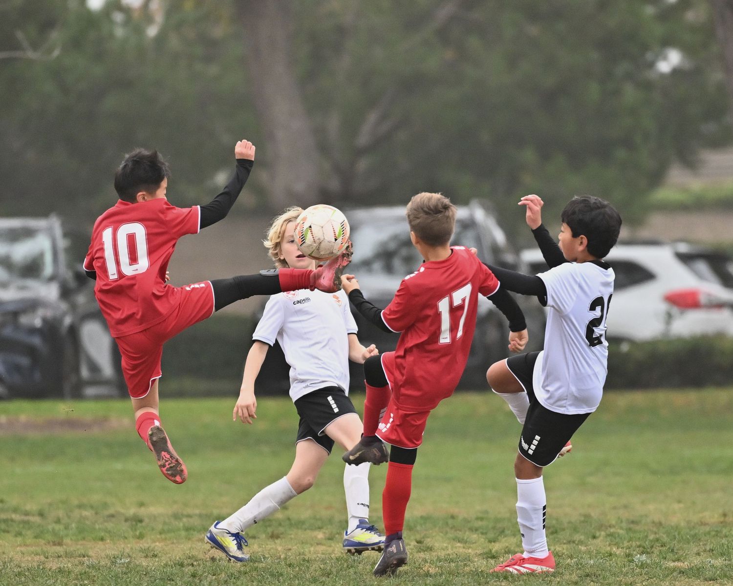 A sequence of soccer players performing bicycle kick moves on a grass field during practice or game action.