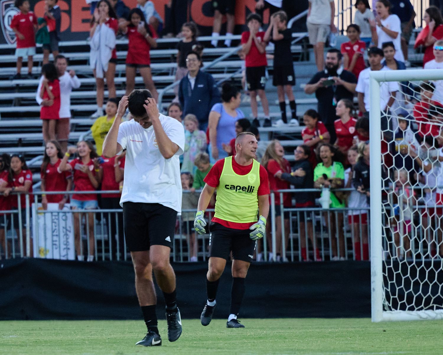A soccer player in a red uniform celebrates after scoring a goal during a match.