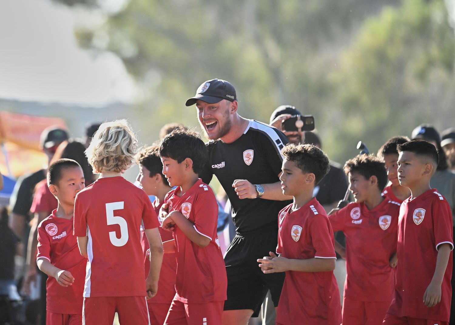 Soccer team in red uniforms standing together on the sideline during a match.