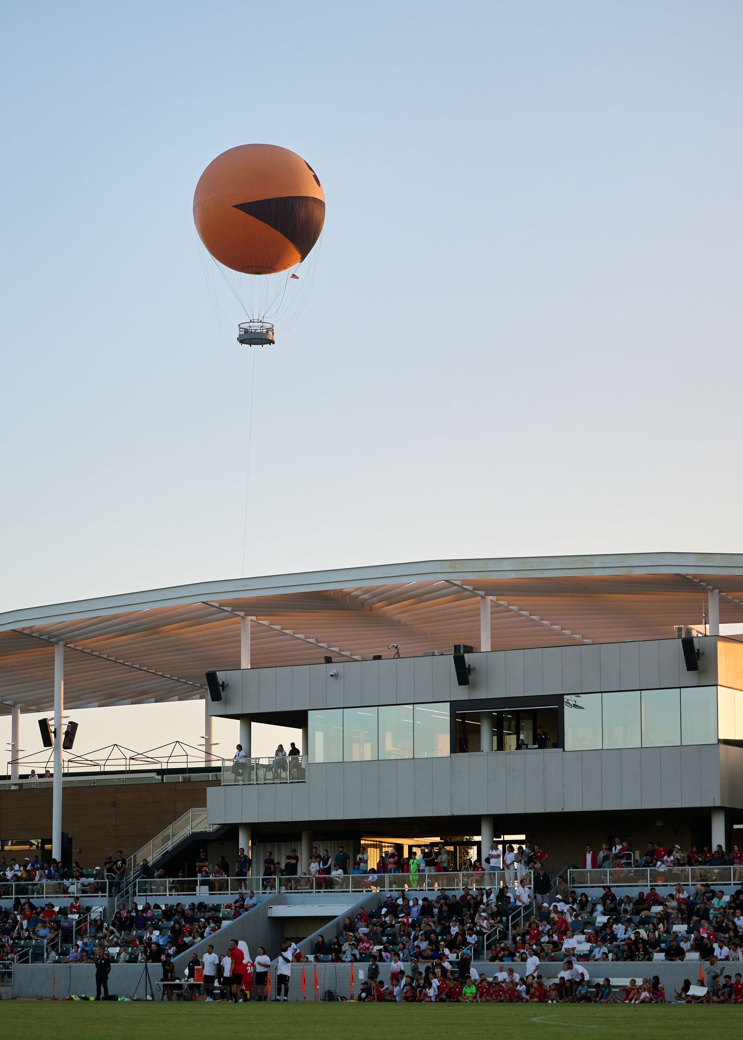 A panoramic view of a modern sports stadium with curved architecture and spectator seating under a clear sky.