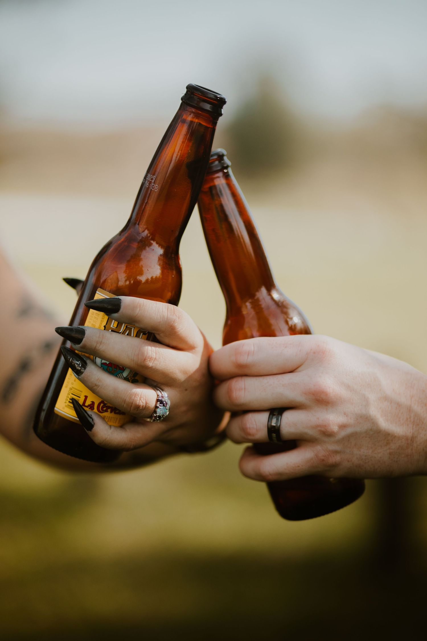 A bride and groom cheers their beer bottles, outdoor scene blurred in background, Richmond photographer, rachel gorth, armory photography