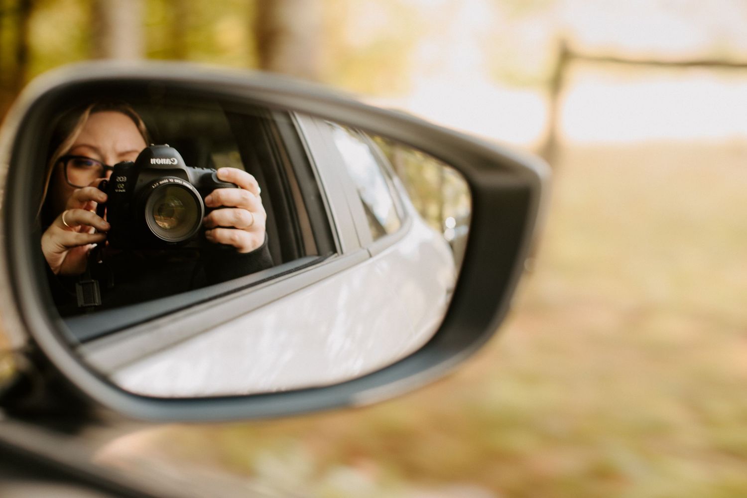 self portrait of photographer in car side mirror