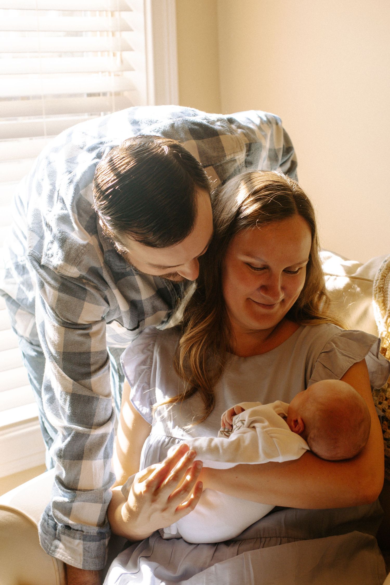 New mom and dad hold their baby in a rocking chair by the window, Richmond photographer, rachel gorth, armory photography