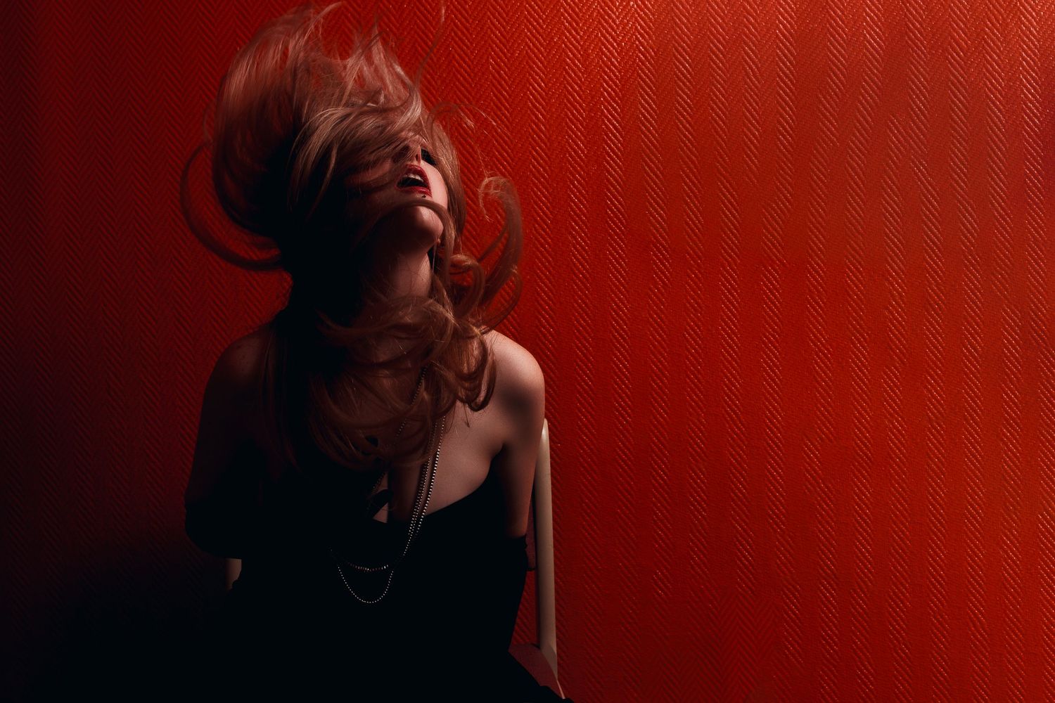 Dramatic portrait against red wall with hair motion.