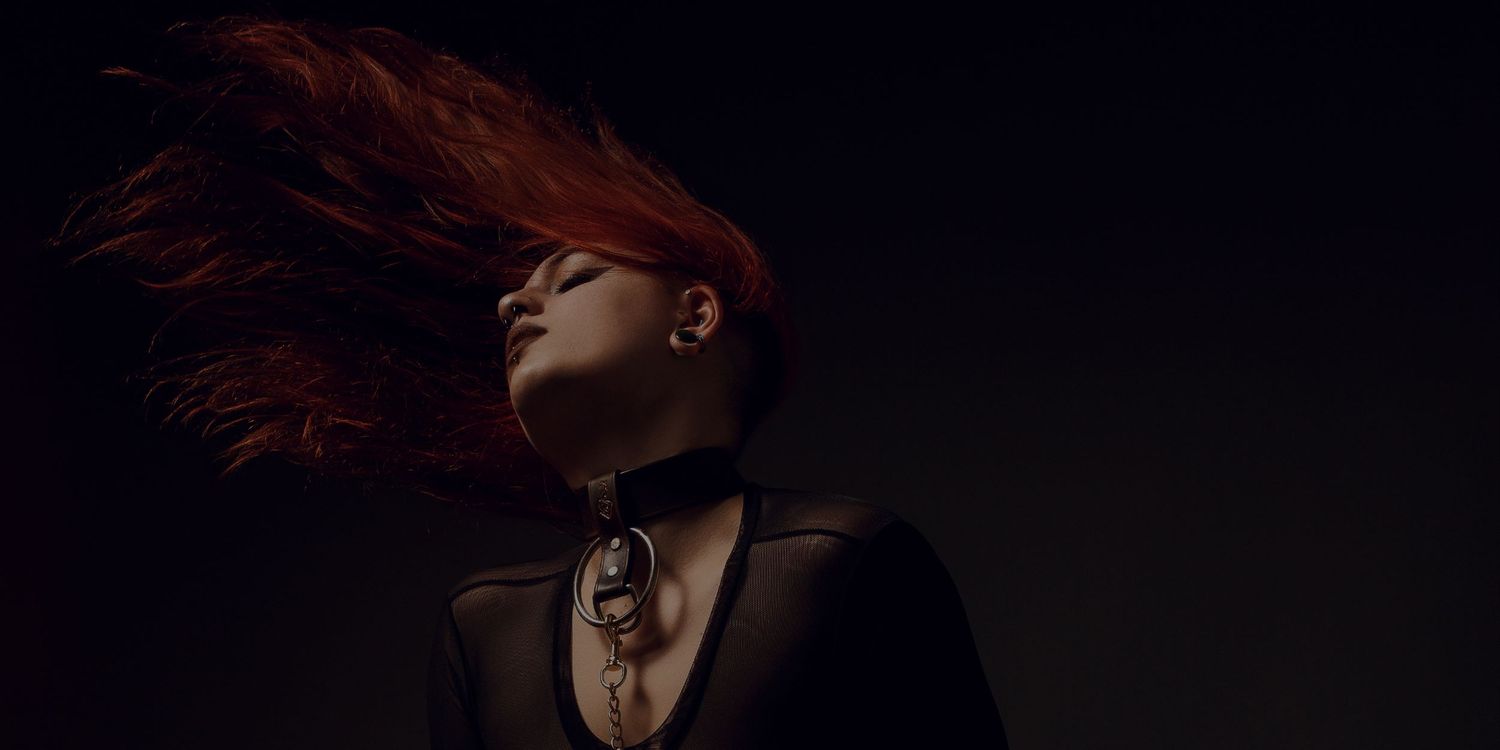 Low-key portrait with dramatic side lighting against dark background.