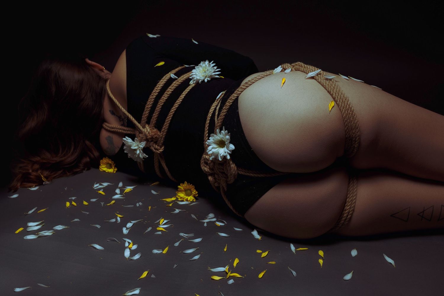 Artistic still life with flowers and scattered petals in moody lighting.