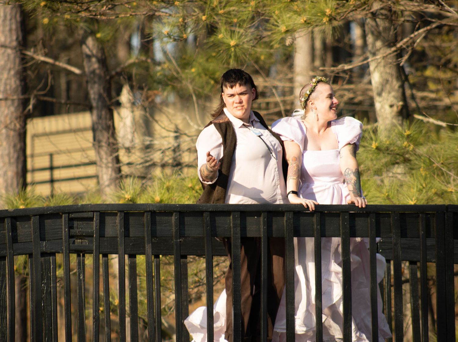 Bride and groom standing together on a bridge surrounded by pine trees during an outdoor wedding.
