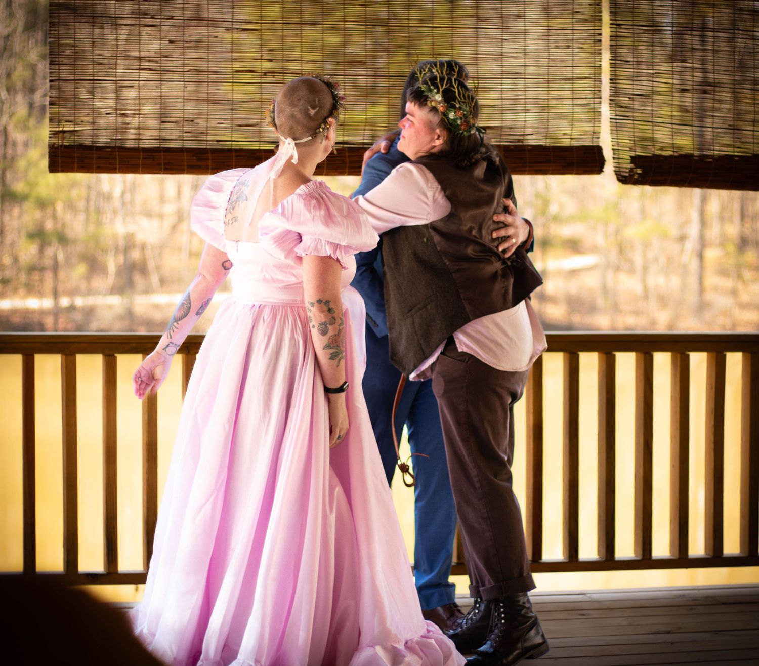 Couple in fairy tale costumes embracing during outdoor wedding ceremony on rustic wooden deck.