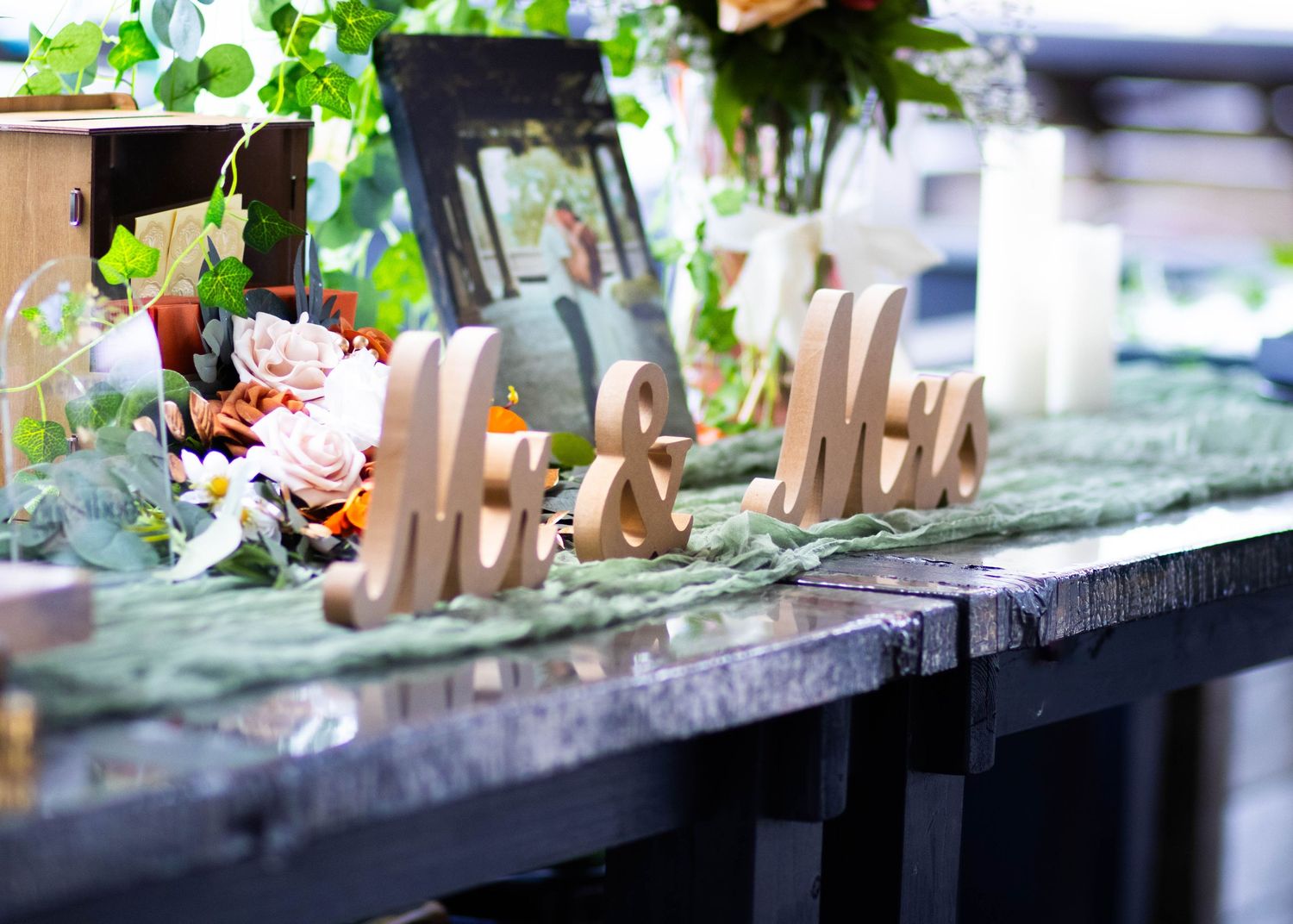 Wooden Mr. & Mrs. signs on a decorated wedding table with floral arrangements and greenery.