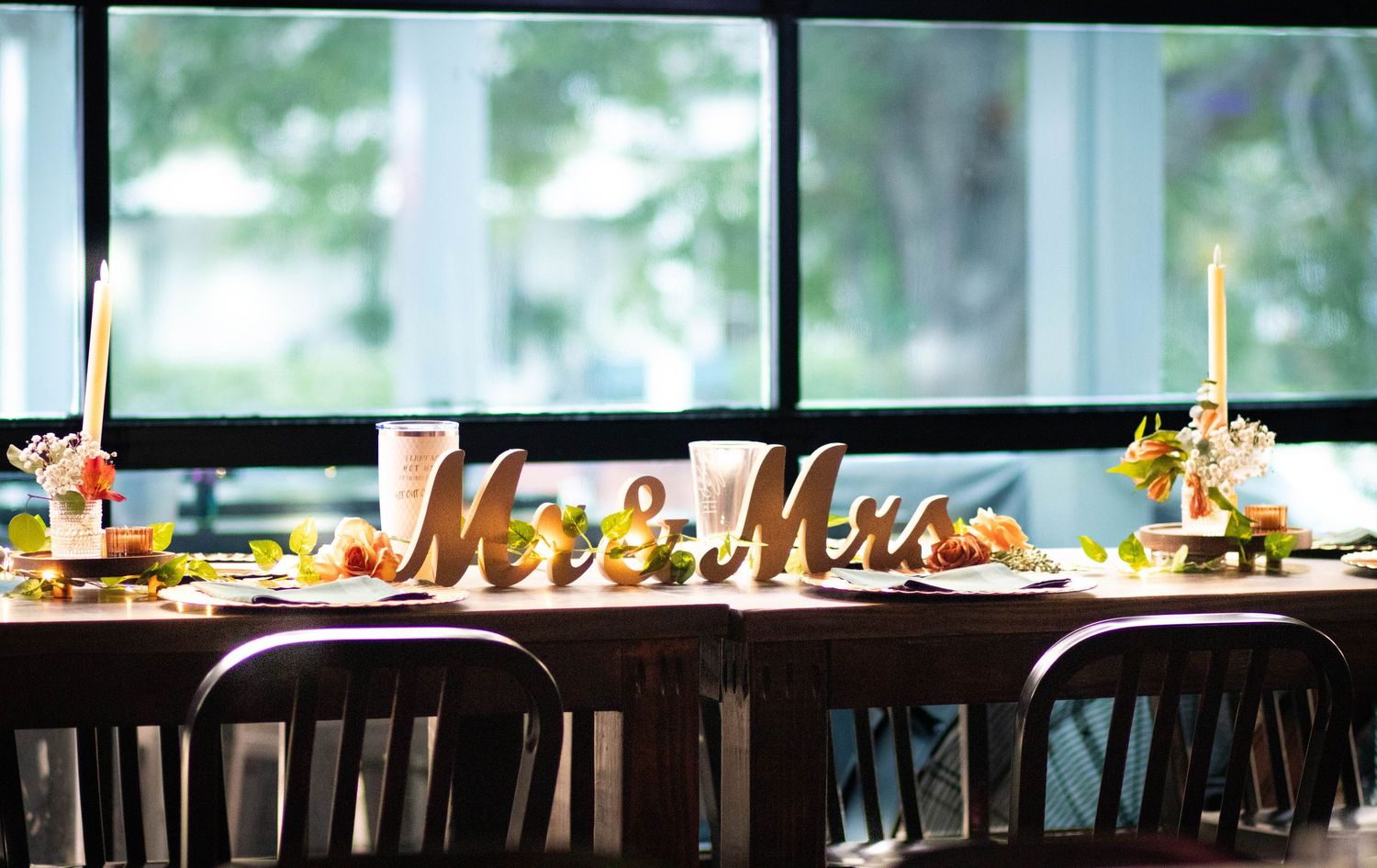 Elegant wedding reception table decorated with Mr and Mrs wooden sign, candles, and colorful floral centerpieces.