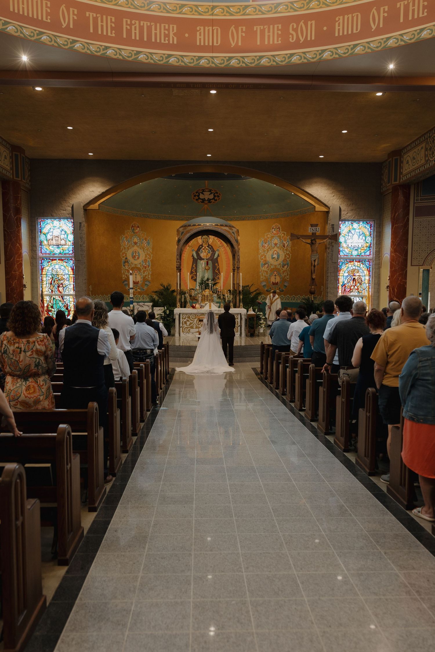 Interior view of a traditional church with stained glass windows and wooden pews during a ceremony.