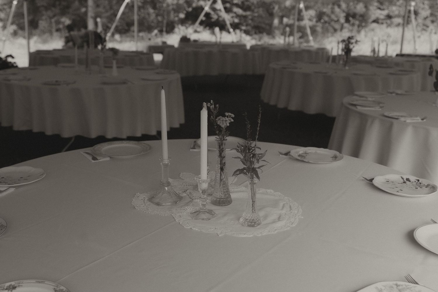 Black and white photo of an elegant round table set with candles and floral centerpiece for a formal event.