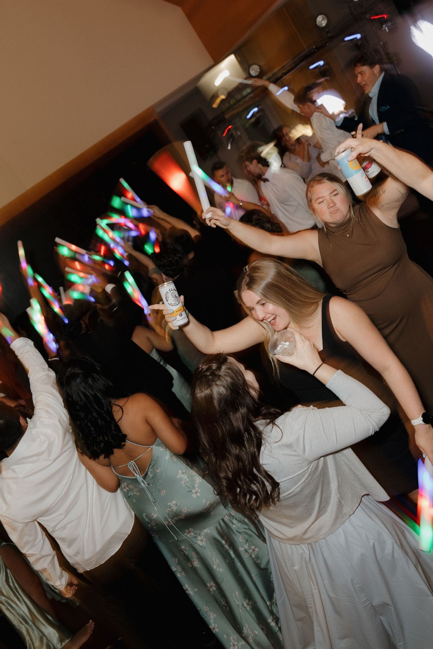 Wedding guests dancing energetically under colorful party lights.