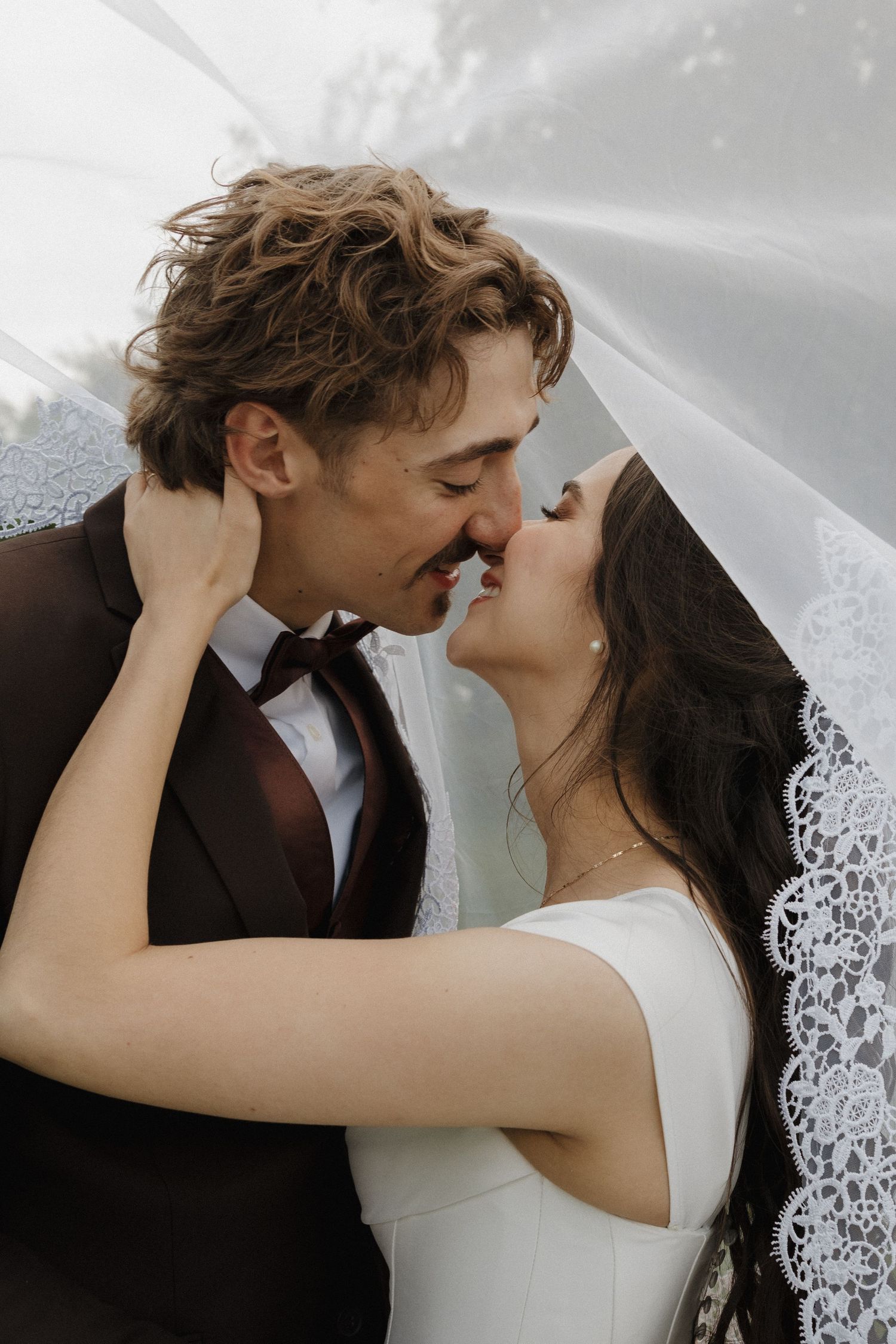 A tender moment between newlyweds as they share an intimate kiss under a delicate lace veil.