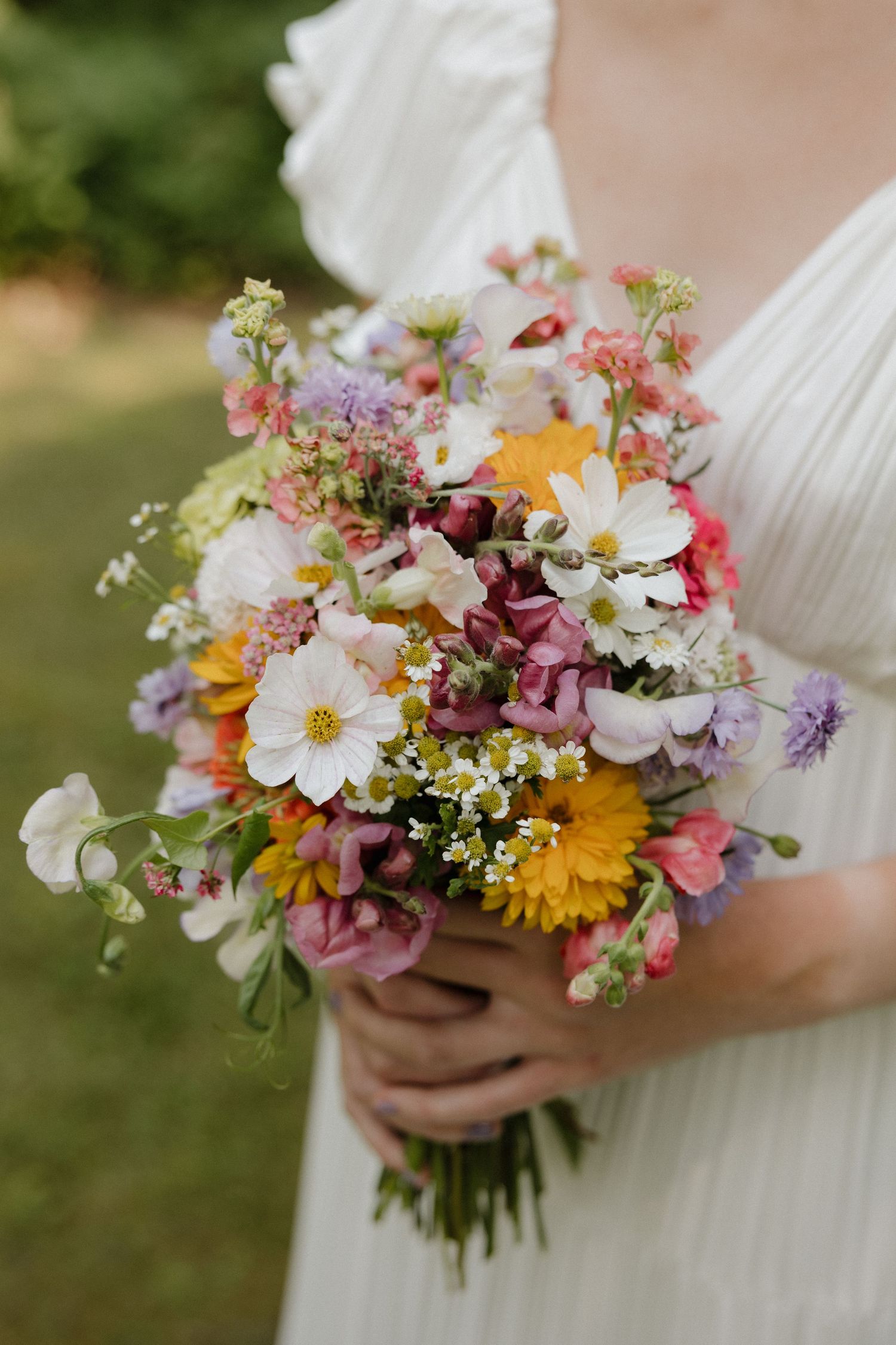 Vibrant wildflower wedding bouquet with cosmos, daisies, and mixed summer blooms.