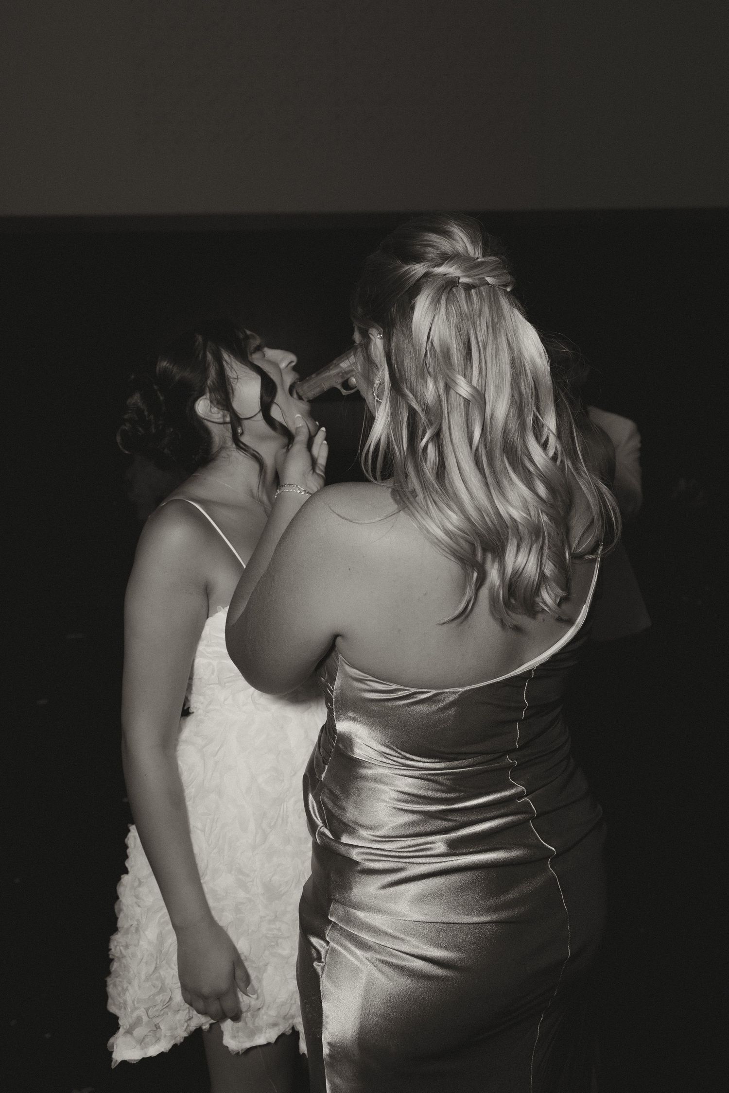 Black and white photo of two people in formal attire embracing at a wedding reception.