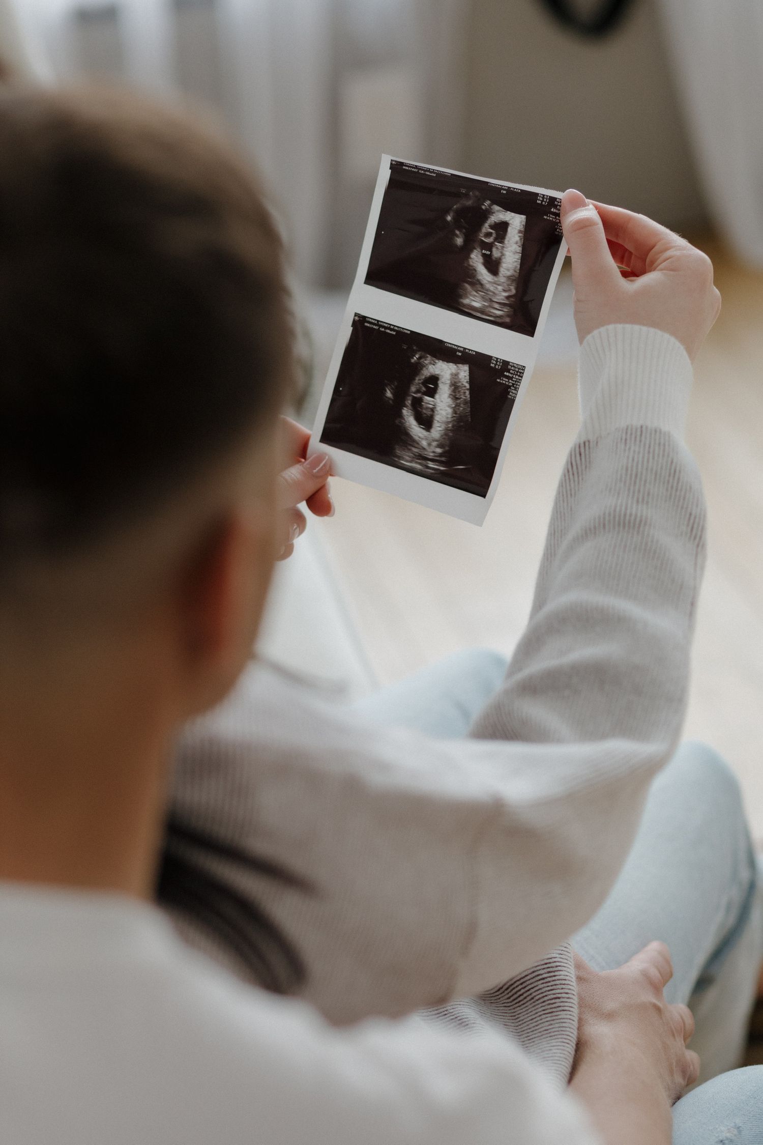 Woman viewing ultrasound photos while sitting on floor.