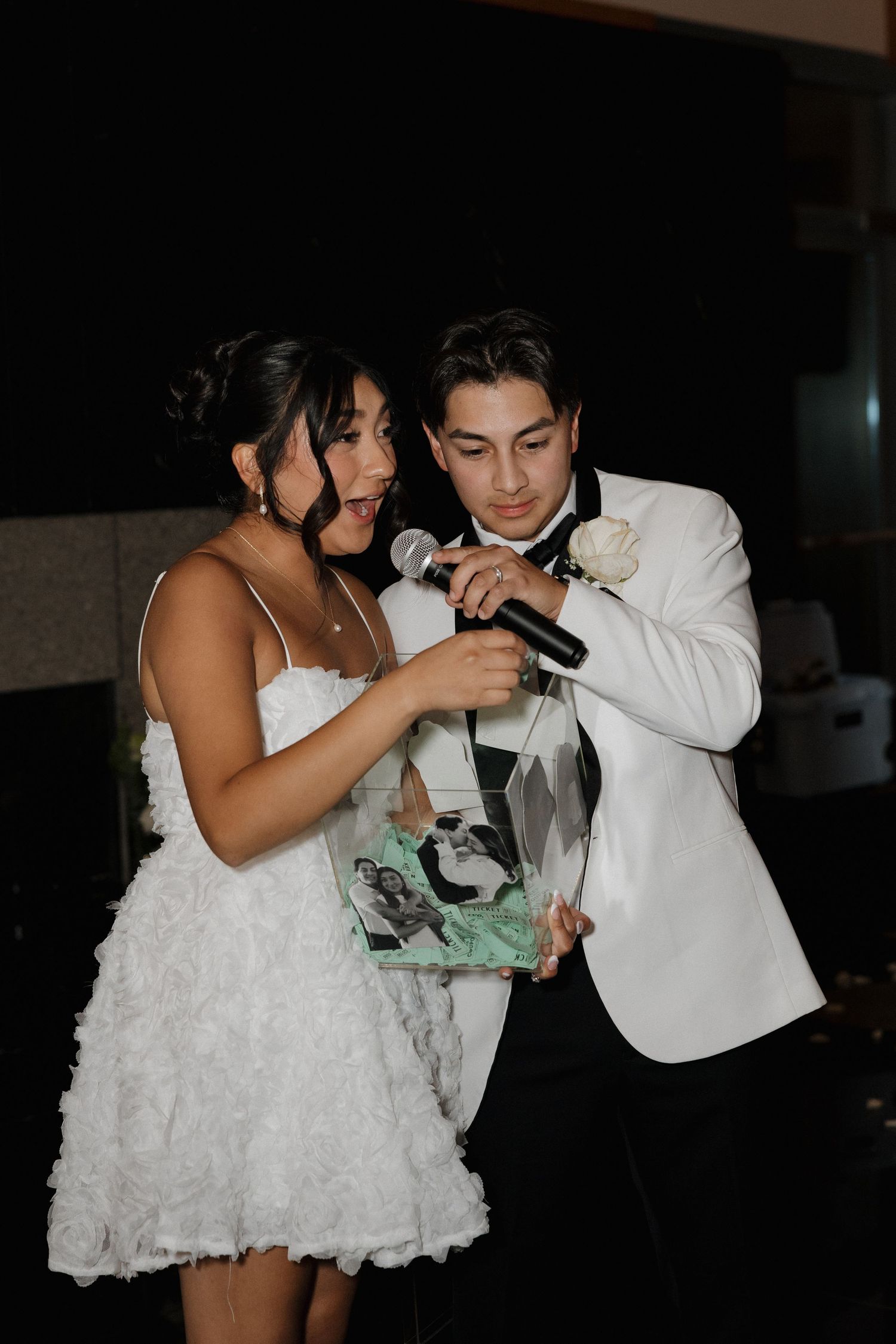 Couple playfully drinking from champagne bottles during wedding reception.