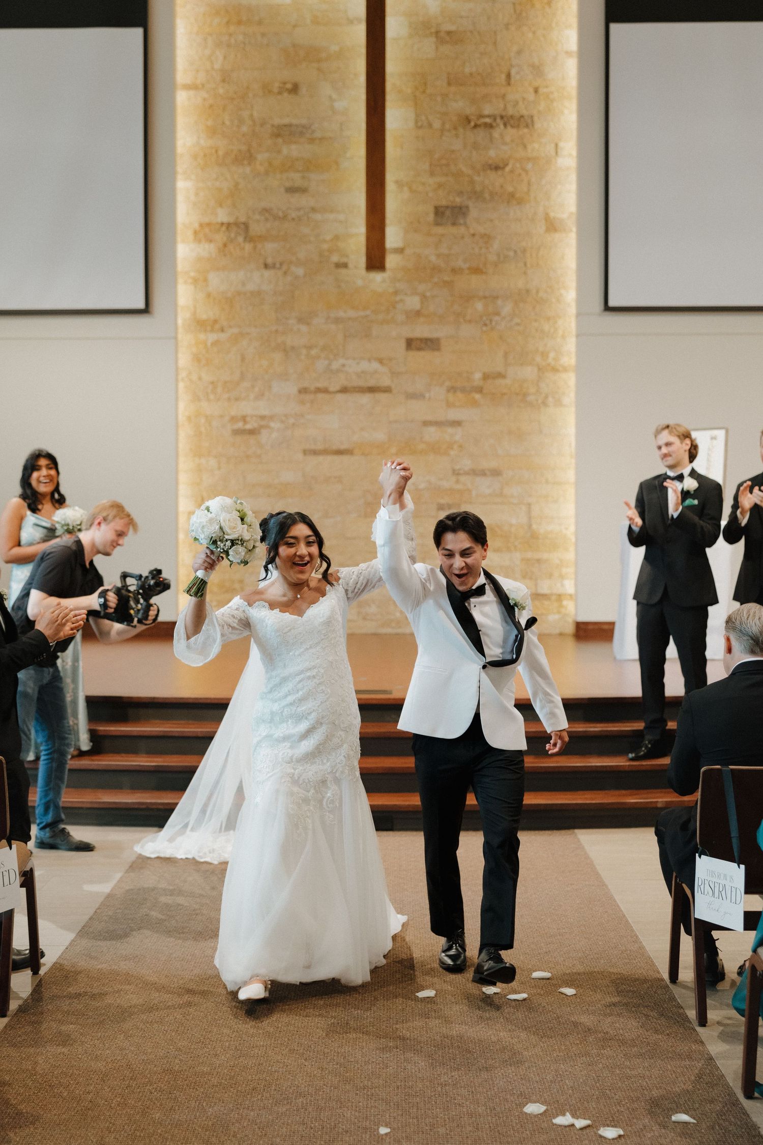 Wedding party members dancing and celebrating together in a church reception hall.
