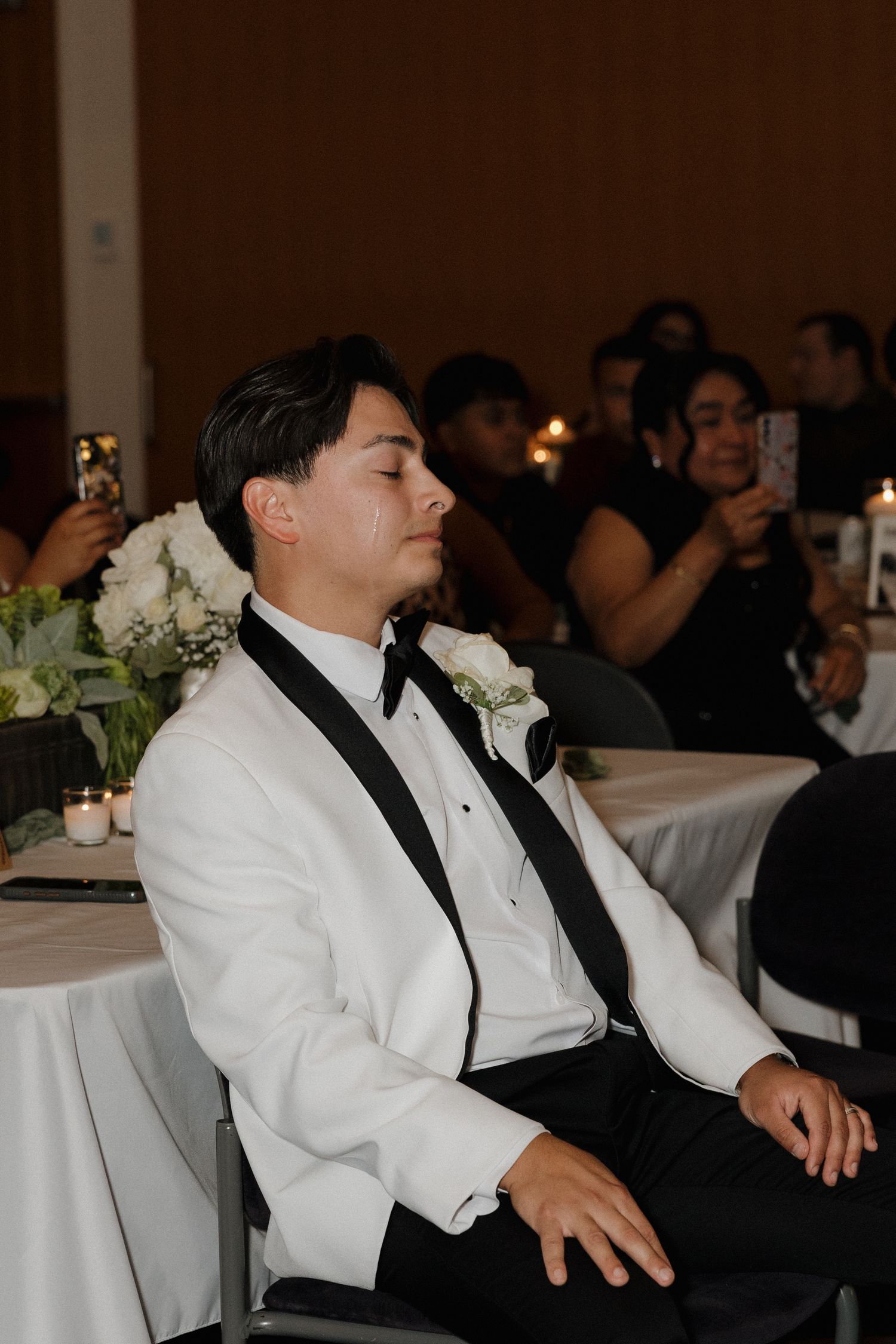 Wedding reception guests in formal attire seated at decorated tables.