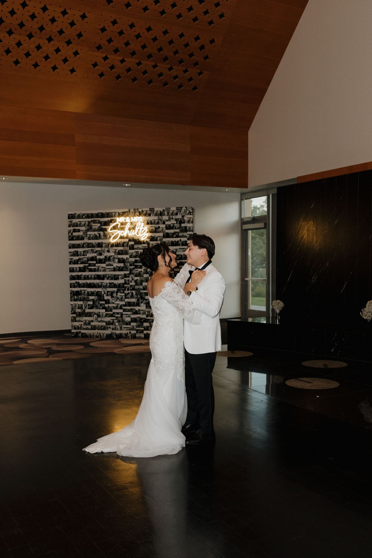 Couple sharing a romantic dance in a modern venue with wooden ceiling and dark floors.