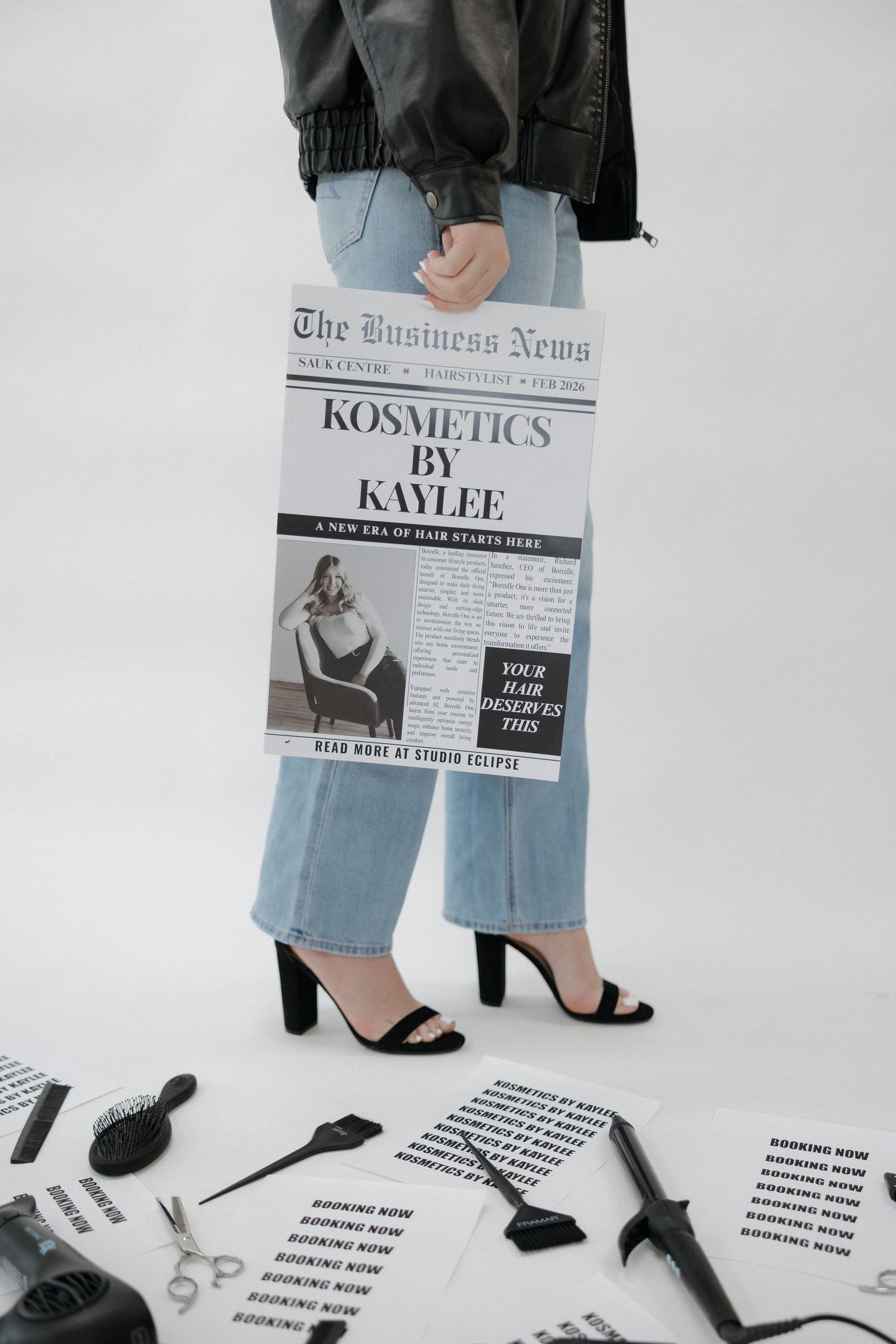 Person holding Kosmetics by Kaylee newspaper ad surrounded by hair tools and booking flyers on floor.
