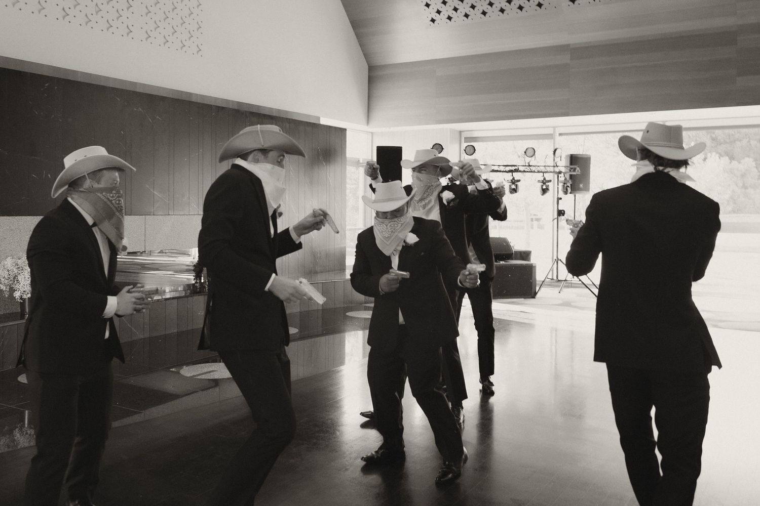 A black and white panoramic view shows silhouettes of people walking through a modern gallery space.