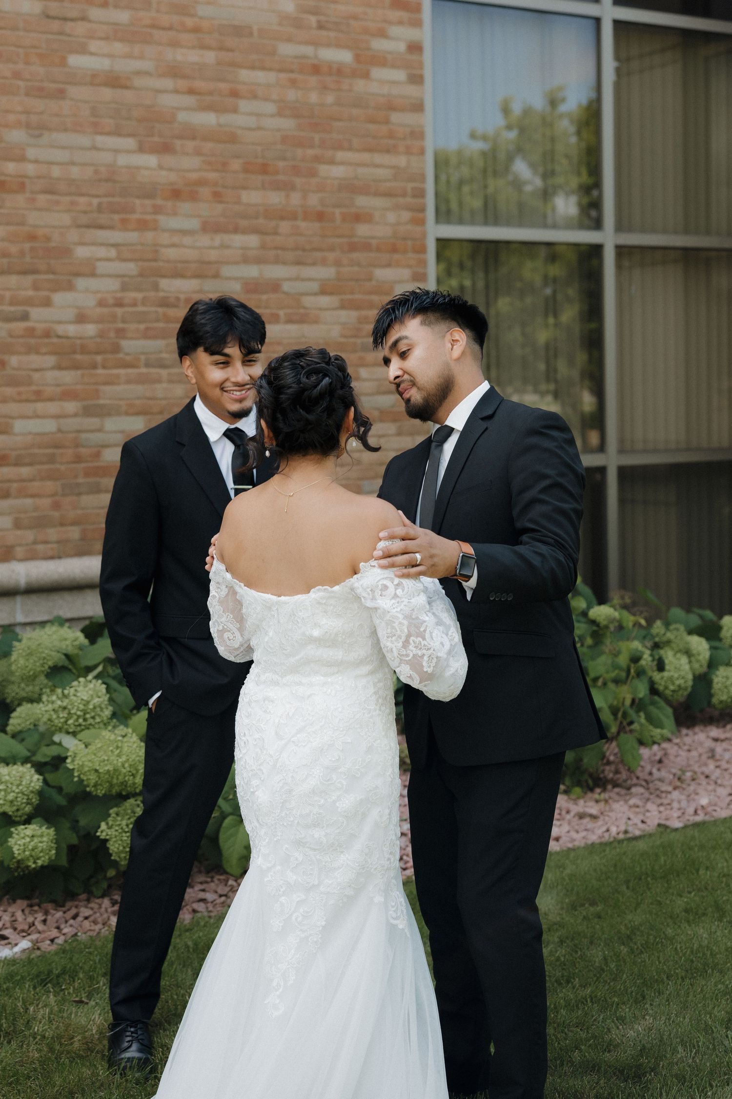 A couple shares an intimate first look moment before their wedding ceremony against a brick building backdrop.