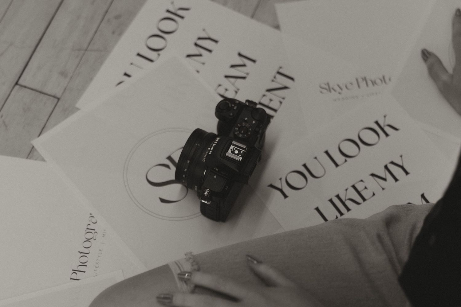 Black and white flatlay of DSLR camera on branded photography prints reading 'You Look Like My Dream Client'.