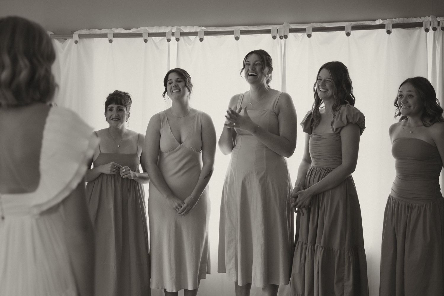 A row of bridesmaids in matching gray dresses pose together before a wedding ceremony.