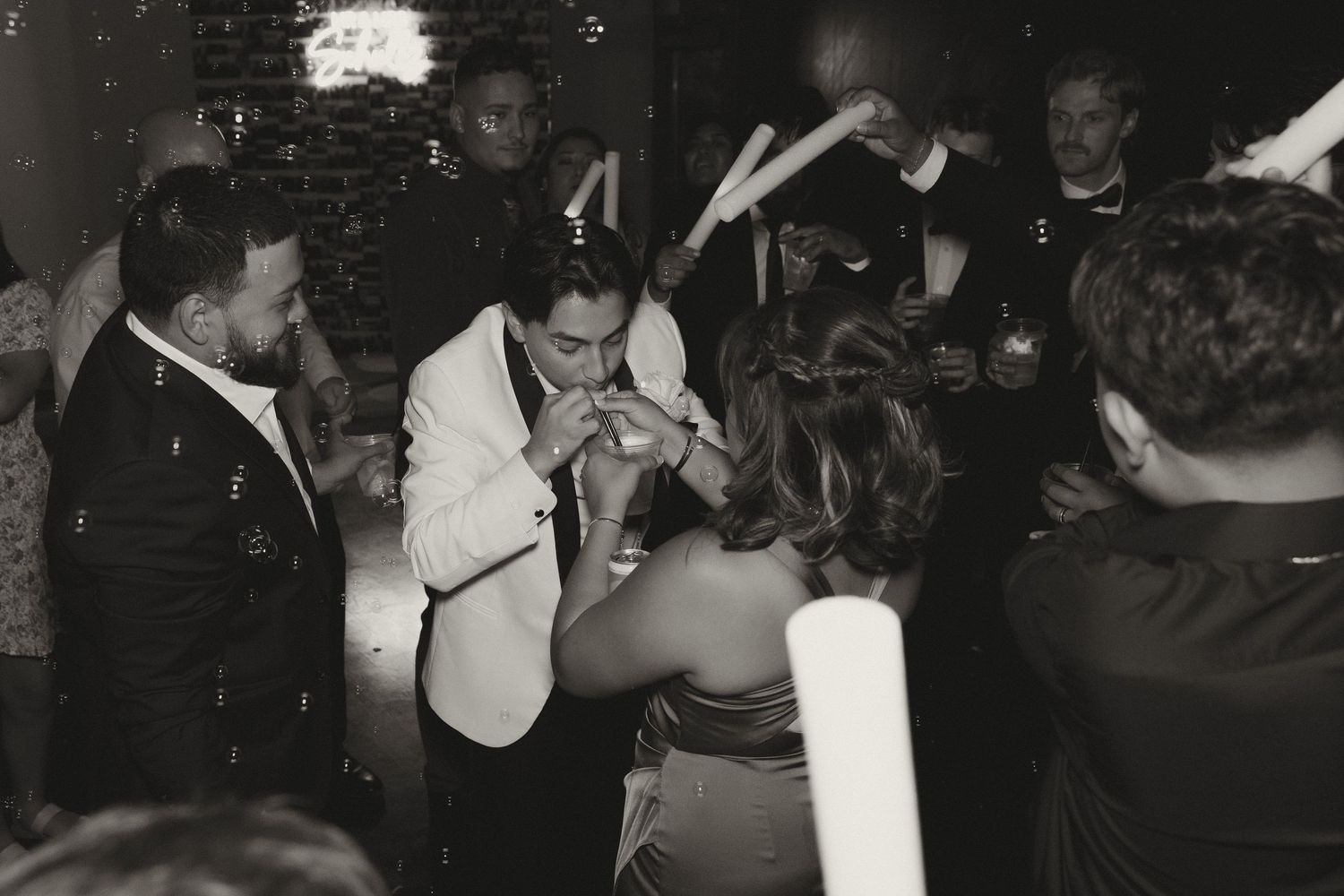 Wedding guests dancing and celebrating at a dimly lit reception.