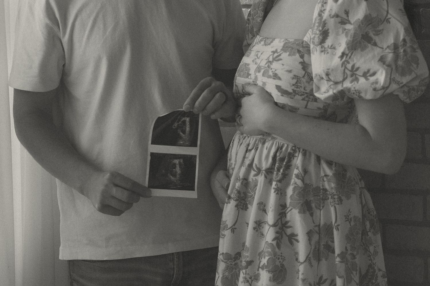 Black and white photo of couple holding ultrasound photos for pregnancy announcement.