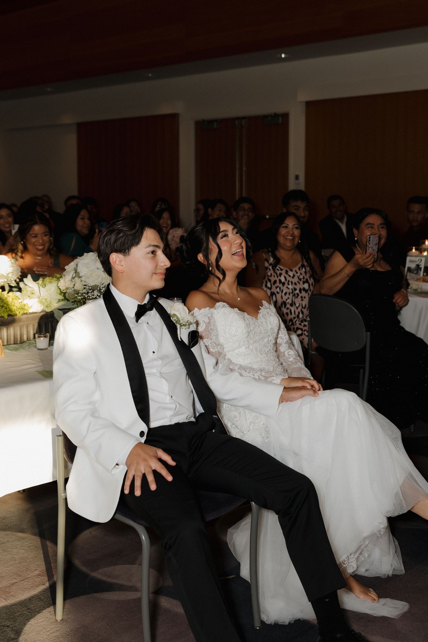 Wedding party seated in formal attire during reception celebration.