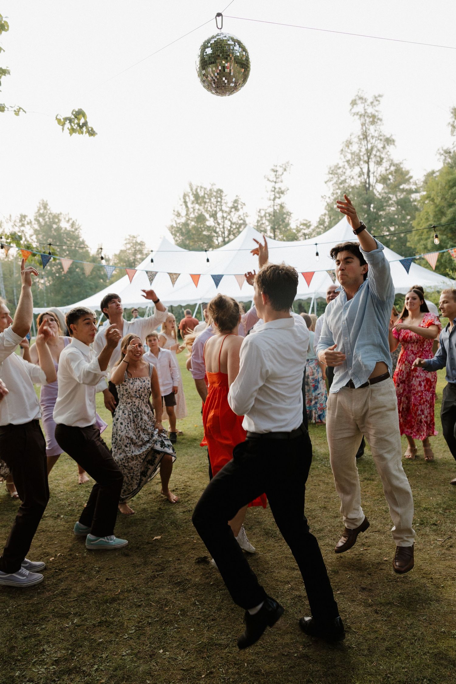 Wedding guests dancing energetically at outdoor evening reception.