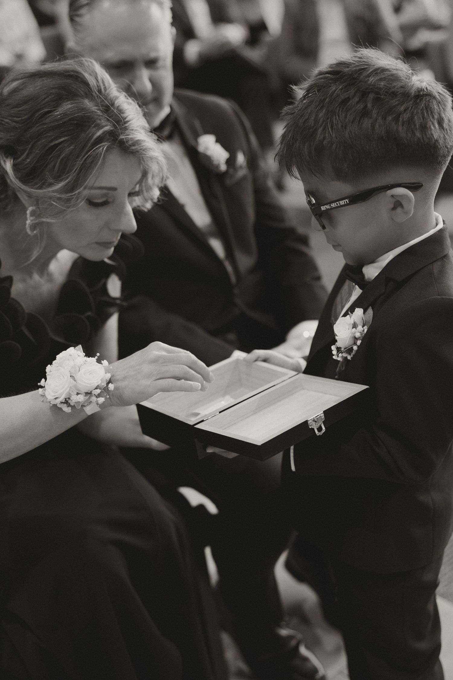 Black and white photo of wedding guests signing guest book at reception.
