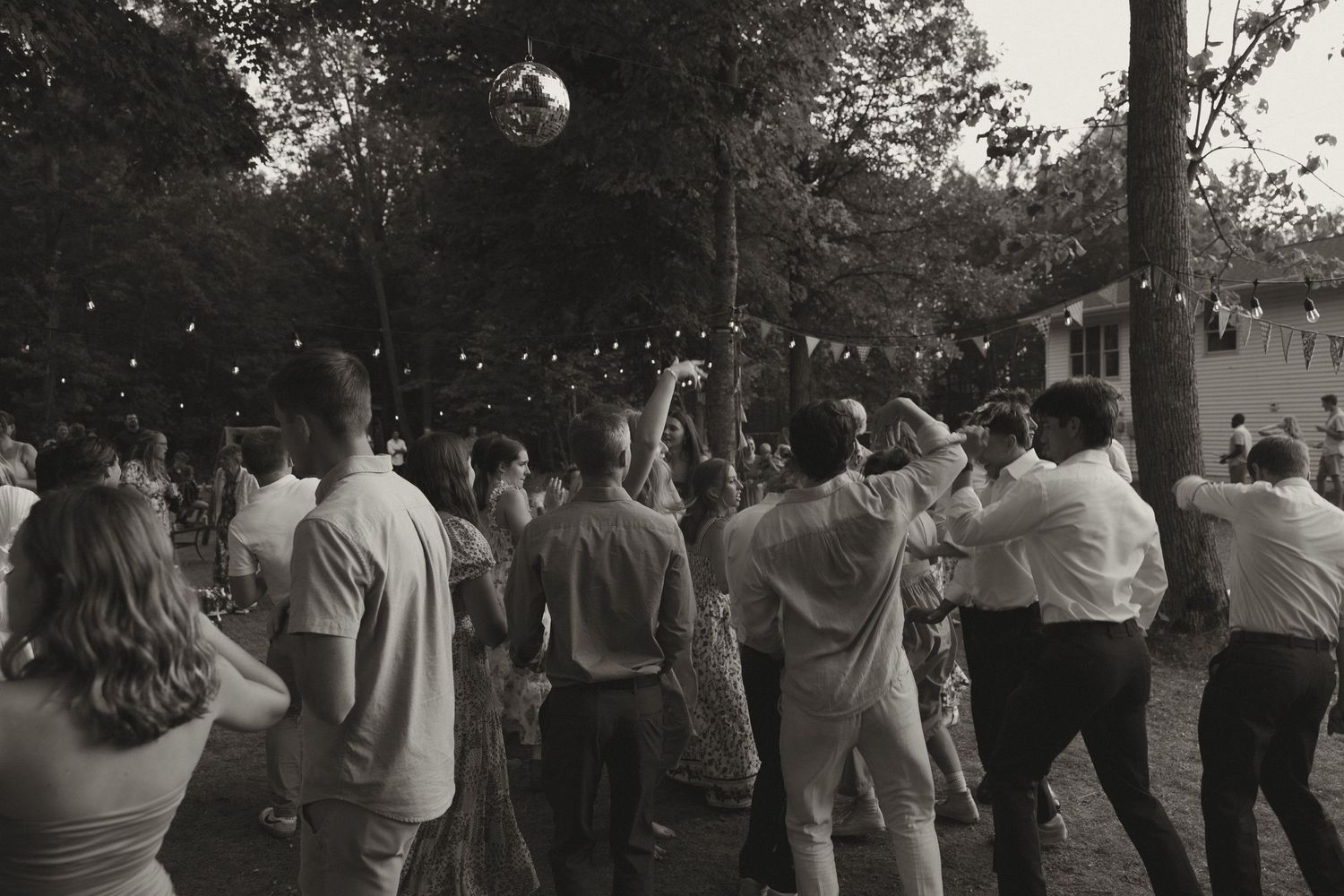 Wedding guests dancing in silhouette during an outdoor evening reception.