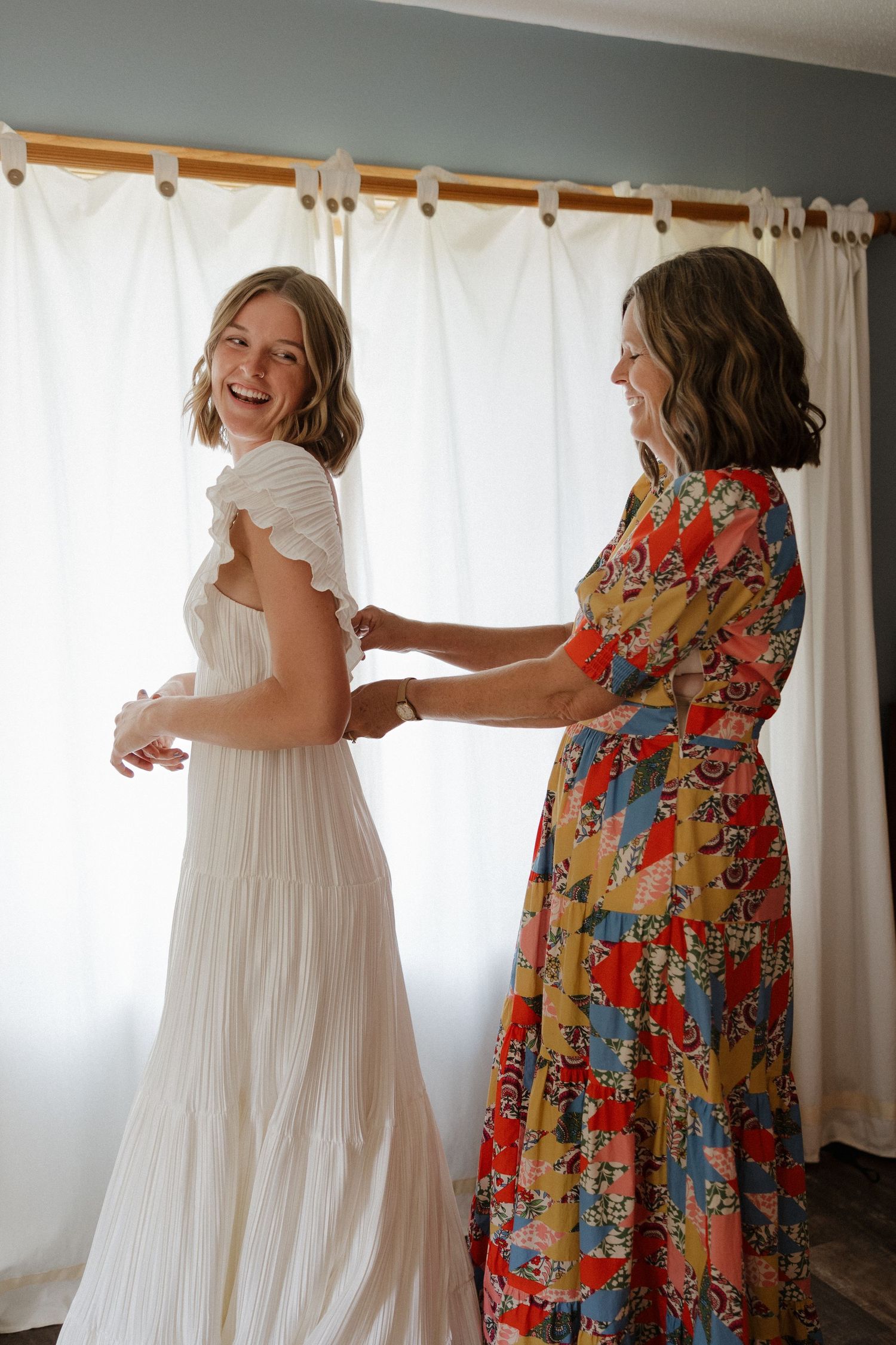 A joyful dance scene showing two people in contrasting dresses - one in white and one in colorful floral print.