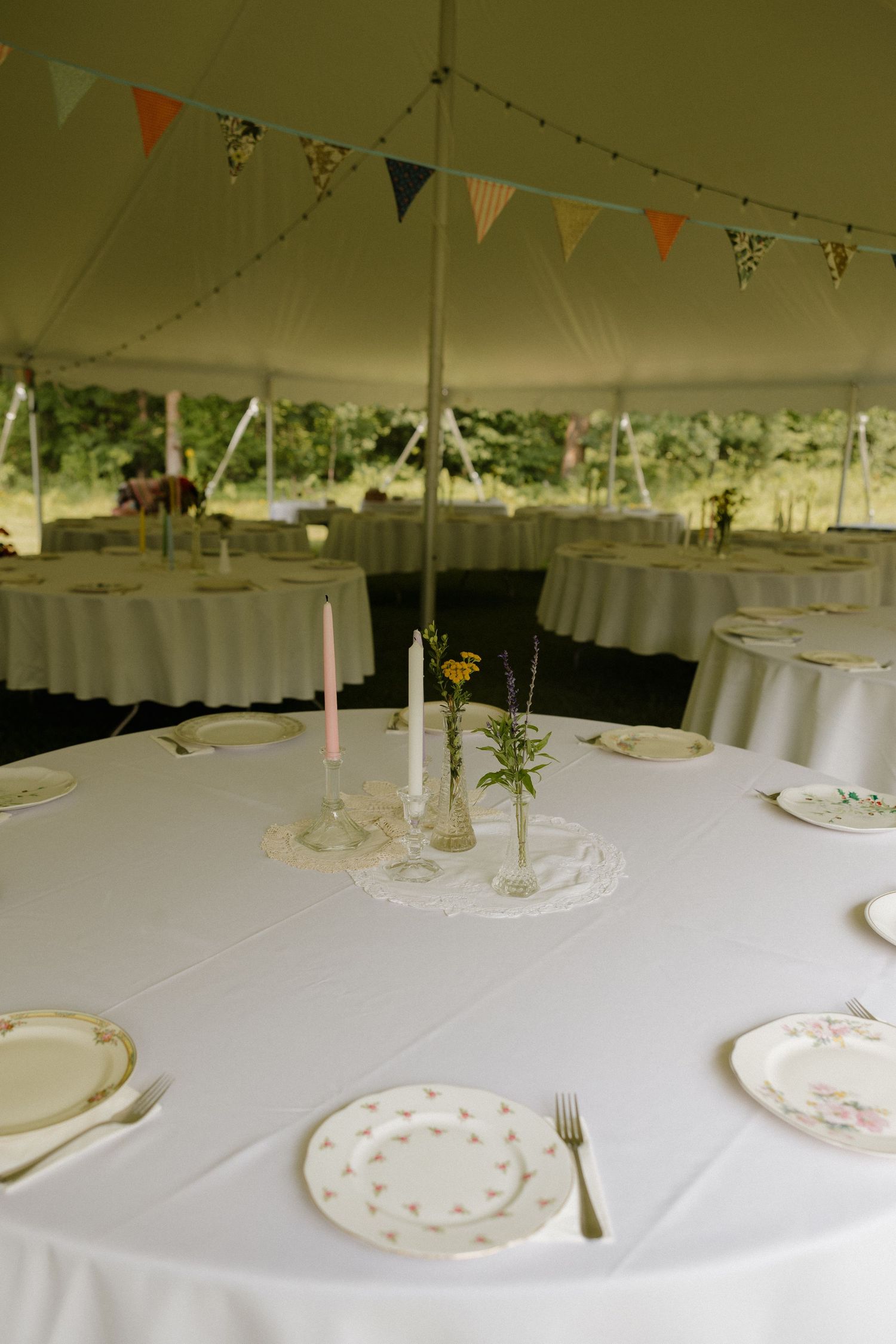 White tablecloths and place settings under a tent with colorful bunting flags strung across the ceiling.