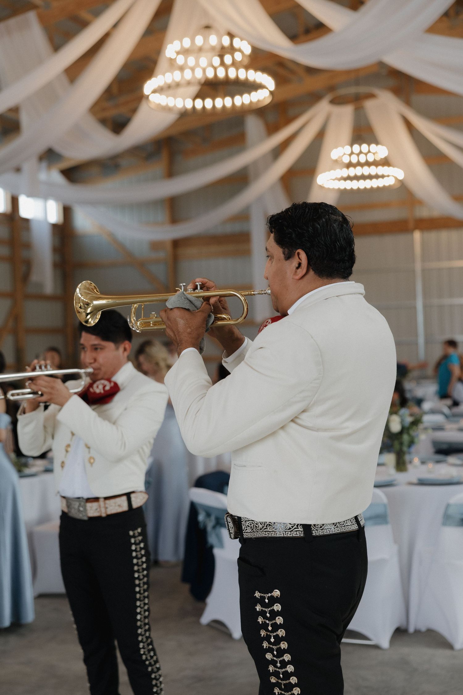 Mariachi band in white jackets performing at a wedding reception.