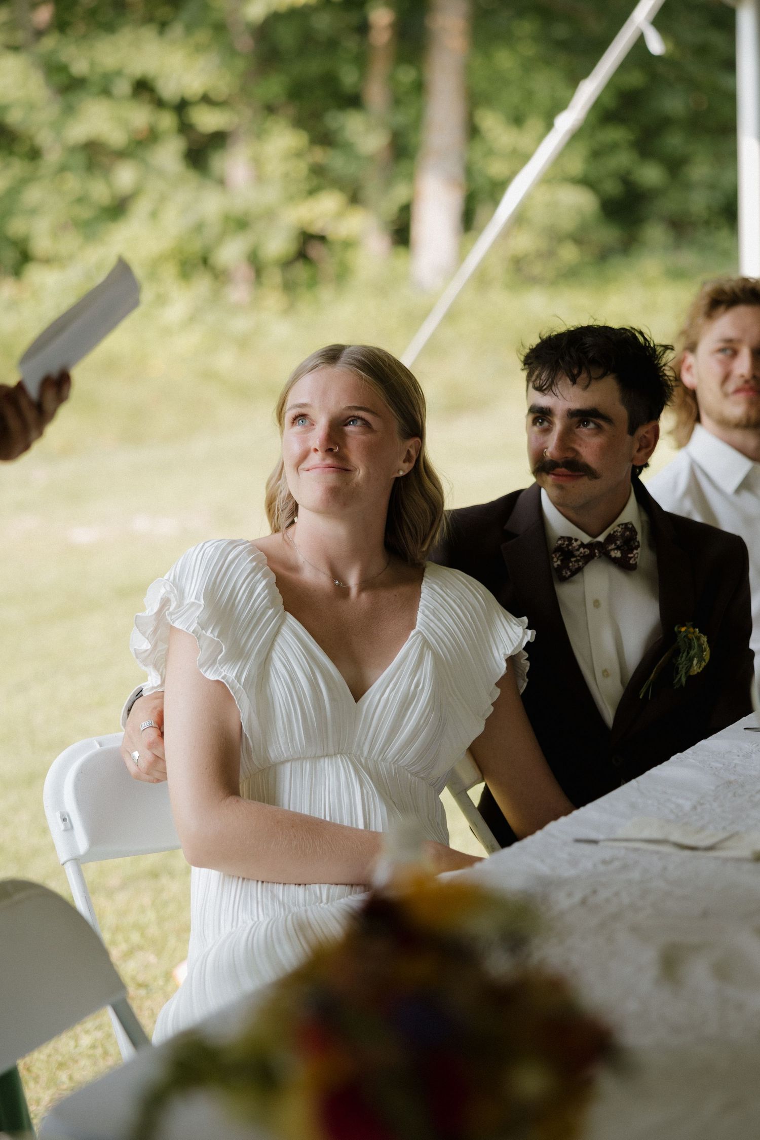Wedding couple sharing laughter during outdoor reception celebration.