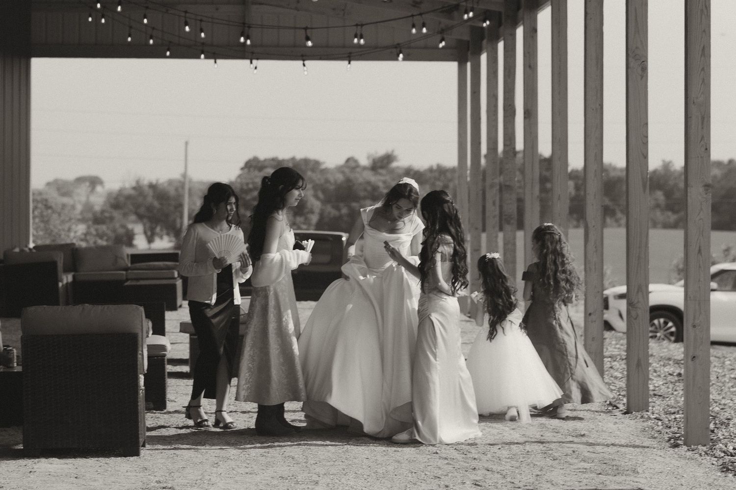 A group of people gather on a covered porch overlooking a scenic landscape during a formal event.