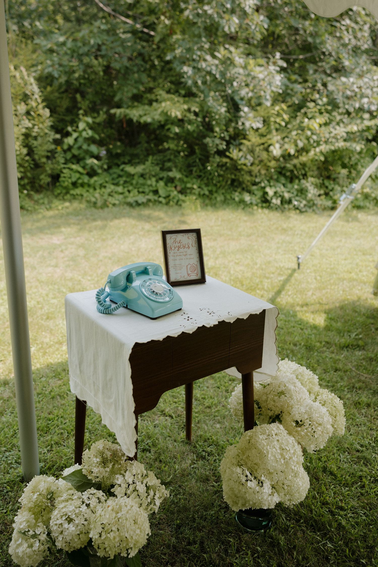 White wedding reception tables decorated with hydrangea flowers set up outdoors.