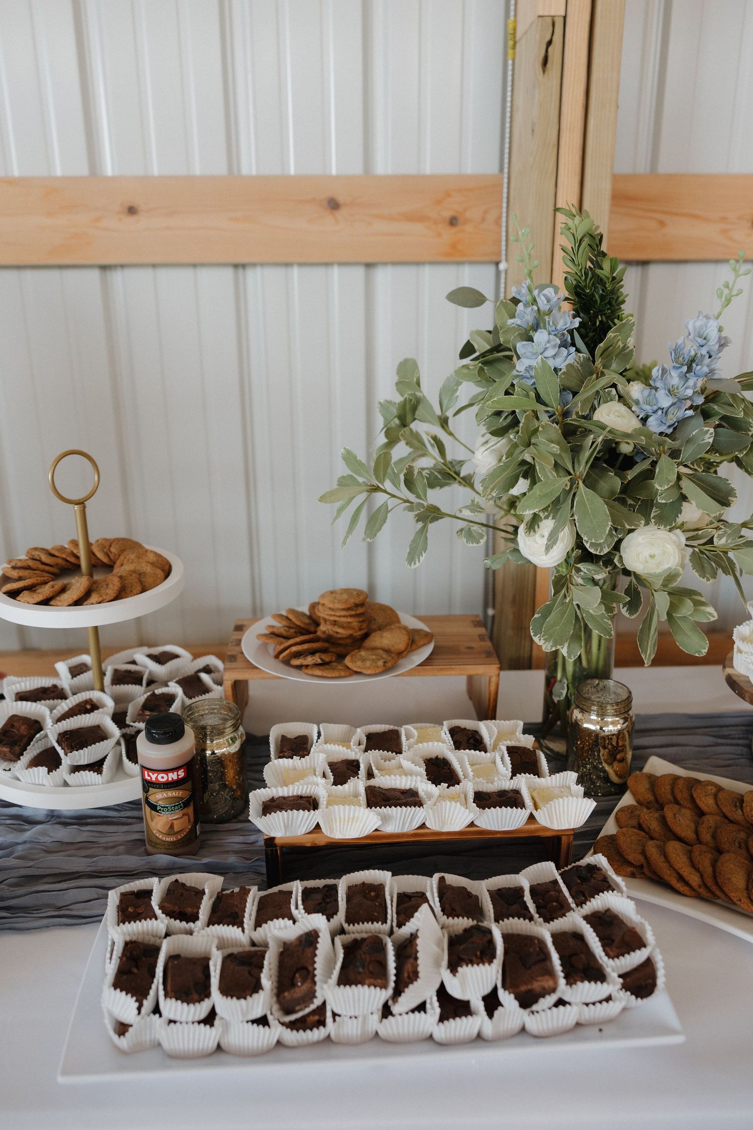 Wedding dessert table with chocolate treats and greenery decorations on rustic wooden display.