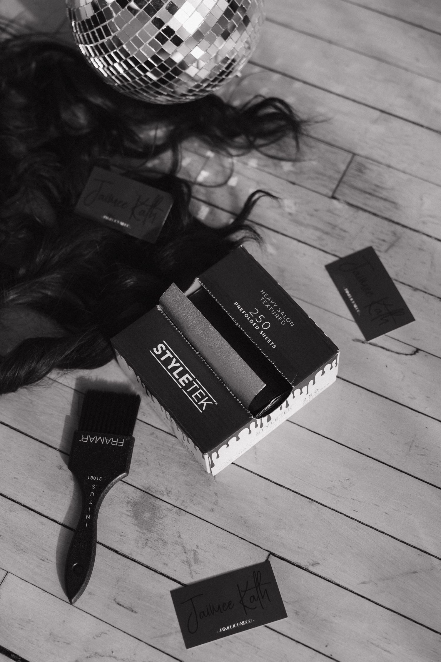 Black and white flat lay of StyleTek foils box, Framar brush, hair, and business cards.